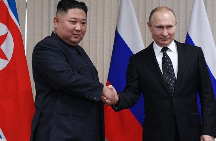 Poignée de main entre Kim Jong-un et Vladimir Poutine devant les drapeaux nord-coréen et russe.
