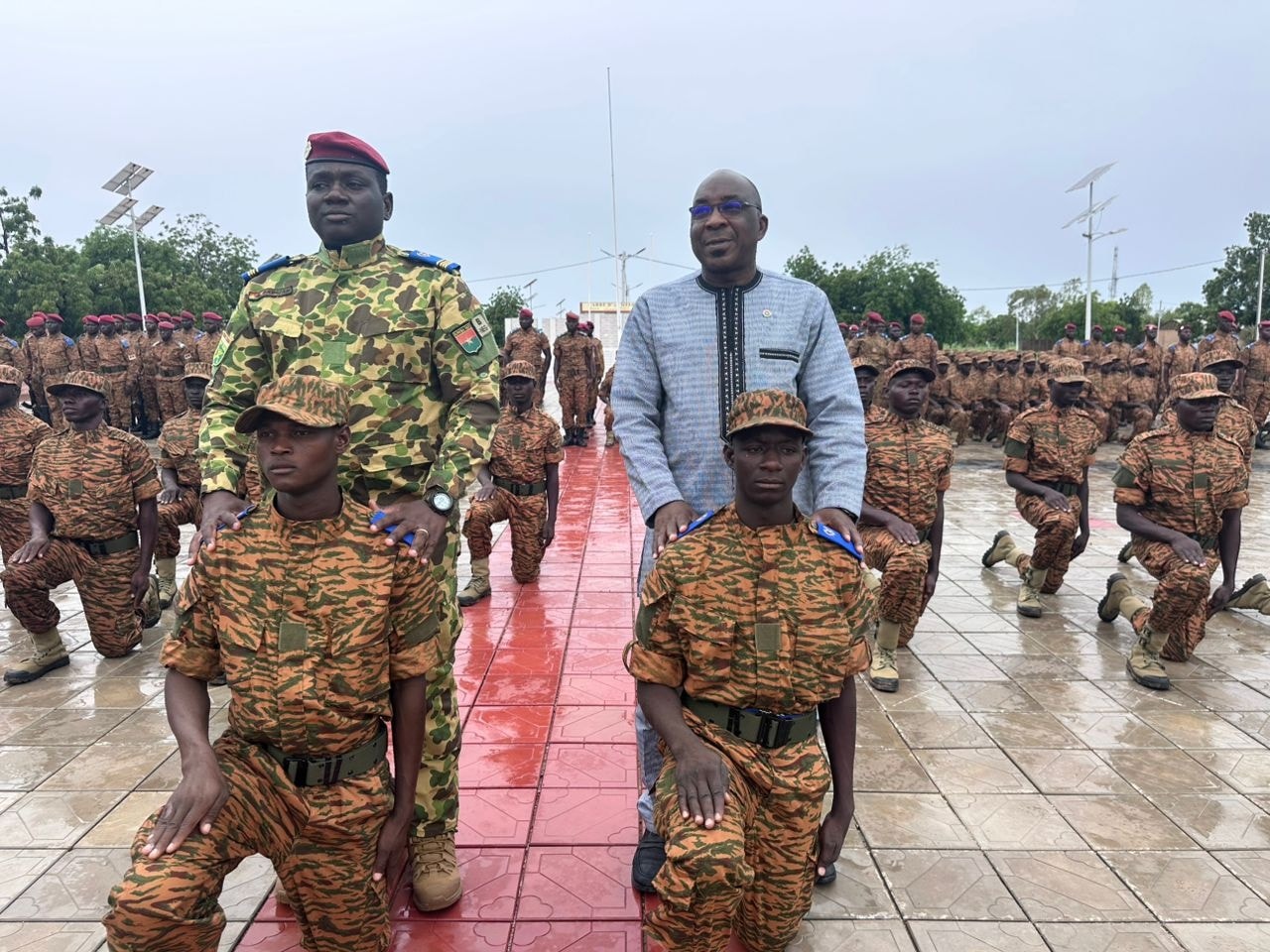 Des autorités militaires et civiles décorent de jeunes soldats burkinabè agenouillés lors d’une cérémonie officielle à Tenkodogo.