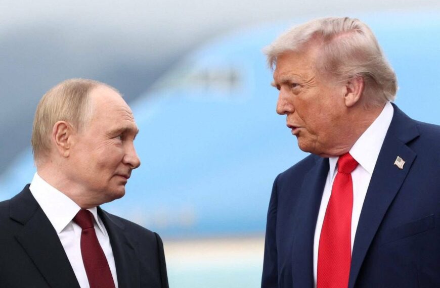 Vladimir Poutine et Donald Trump discutant face à face sur un tarmac, avec un avion flou en arrière-plan.