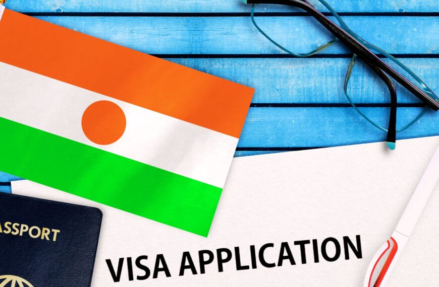 Drapeau du Niger posé sur une table en bois bleu, à côté d’un passeport, d’un formulaire de demande de visa et d’un stylo.