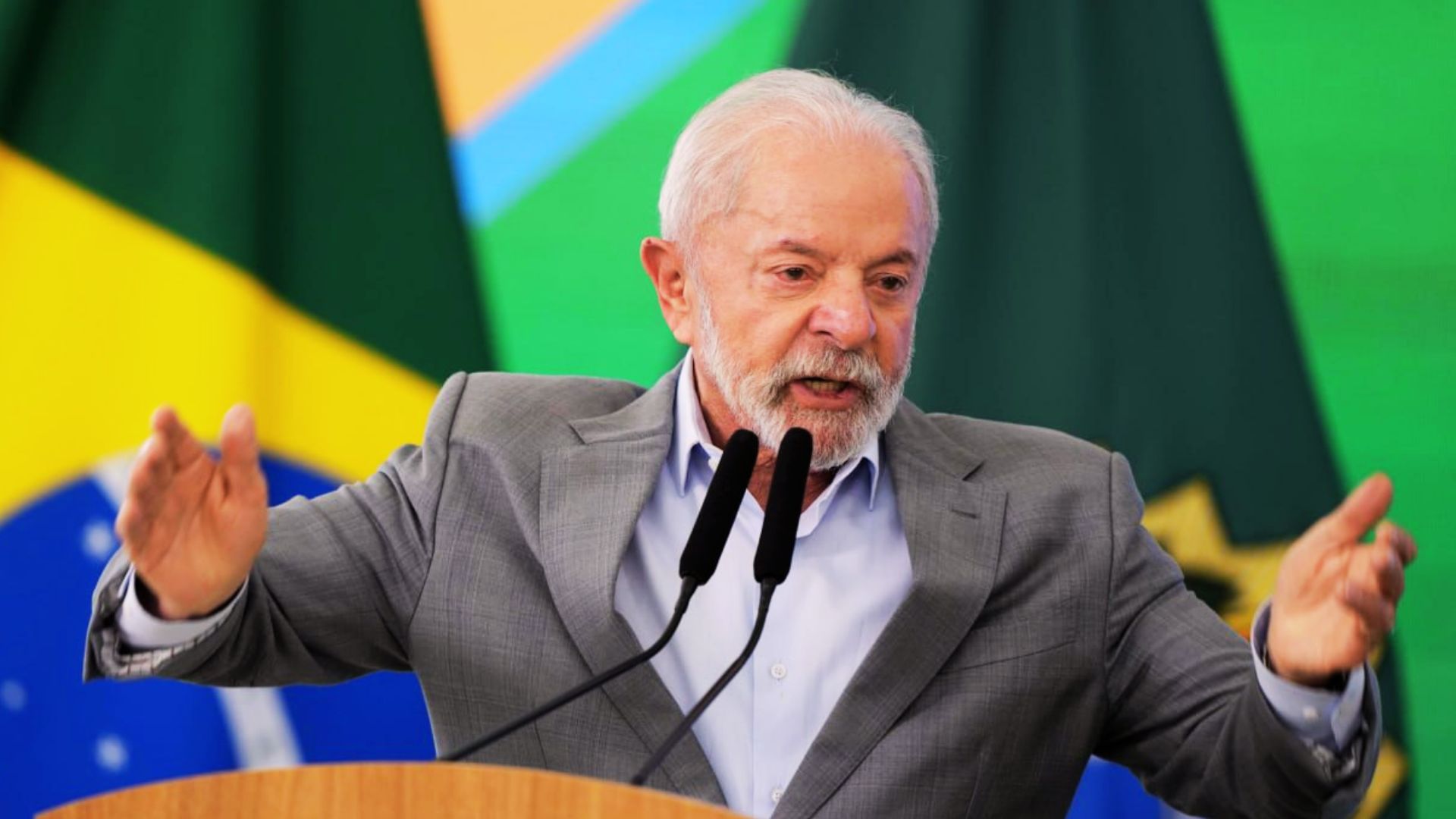 Lula da Silva prononce un discours énergique au pupitre, devant les drapeaux brésiliens.