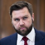 JD Vance en gros plan, costume bleu et cravate rouge.