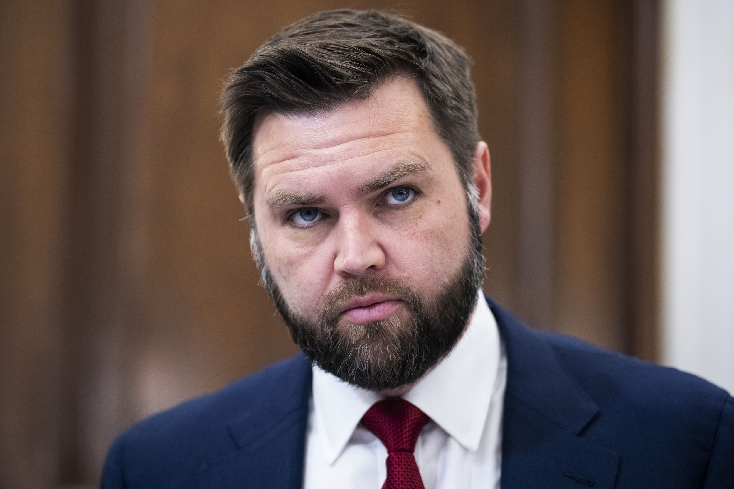 JD Vance en gros plan, costume bleu et cravate rouge.