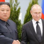 Kim Jong-un et Vladimir Poutine se serrant la main lors d’une rencontre officielle, devant les drapeaux nord-coréen et russe.