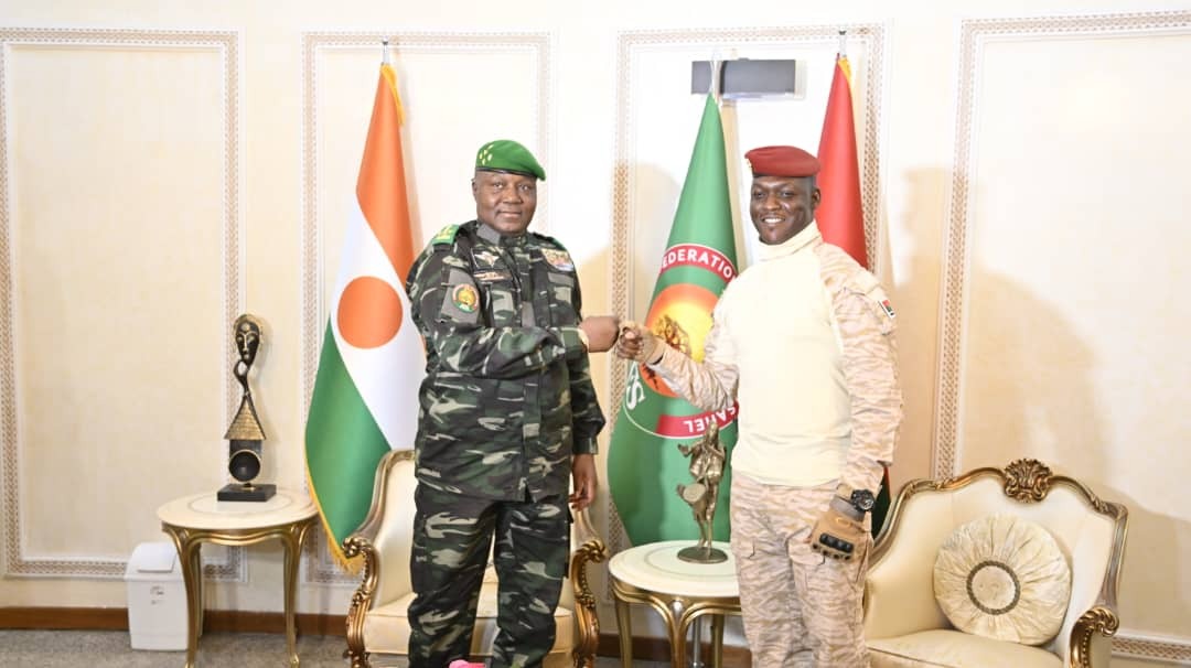 Abdourahamane Tiani et Ibrahim Traoré se serrent la main devant les drapeaux du Niger, du Burkina Faso et de l’AES.