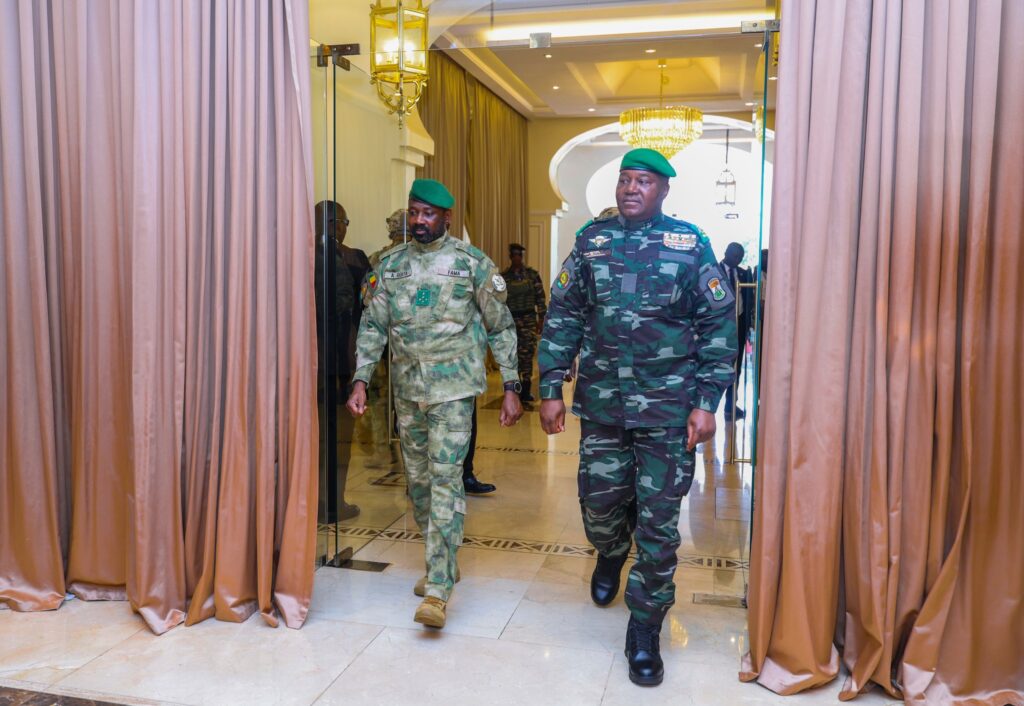 Le président malien Assimi Goïta (à droite) et le président nigérien Abdourahamane Tiani (à gauche), en tenue militaire avec béret vert, marchent côte à côte dans un couloir officiel à Bamako.