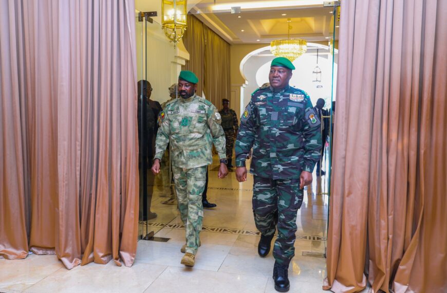 Le président malien Assimi Goïta (à droite) et le président nigérien Abdourahamane Tiani (à gauche), en tenue militaire avec béret vert, marchent côte à côte dans un couloir officiel à Bamako.