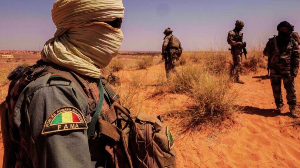 Soldats des Forces Armées Maliennes (FAMa) en patrouille dans une zone désertique, équipés et surveillant le terrain.