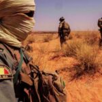 Soldats des Forces Armées Maliennes (FAMa) en patrouille dans une zone désertique, équipés et surveillant le terrain.