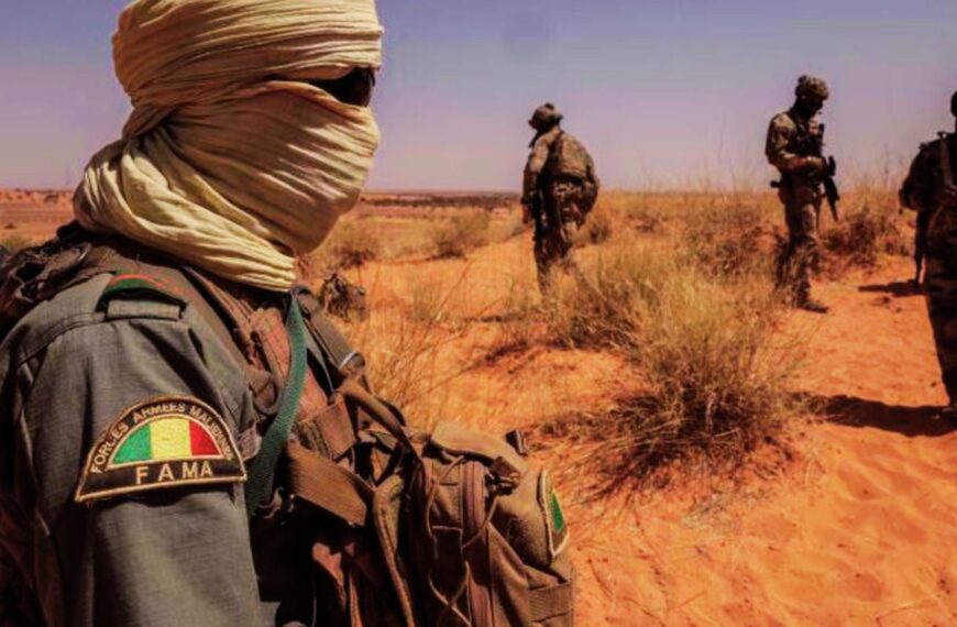 Soldats des Forces Armées Maliennes (FAMa) en patrouille dans une zone désertique, équipés et surveillant le terrain.