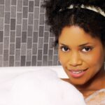 Une jeune femme sort d’une douche froide, ruisselante d’eau, respirant profondément pour se réchauffer, symbole de vitalité et de bien-être naturel.