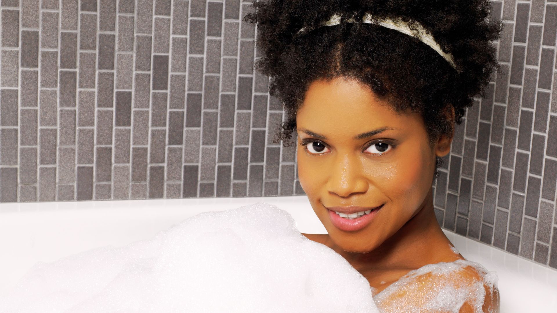 Une jeune femme sort d’une douche froide, ruisselante d’eau, respirant profondément pour se réchauffer, symbole de vitalité et de bien-être naturel.