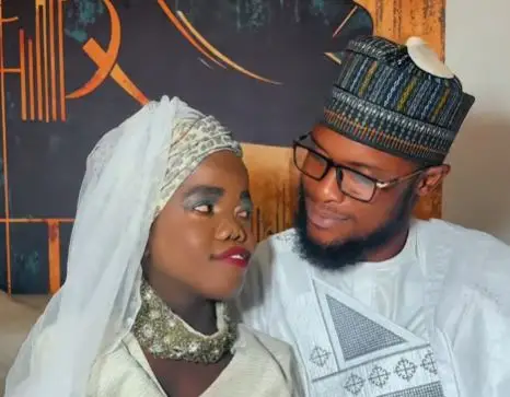 Un couple vêtu de tenues traditionnelles nigérianes regarde l’un vers l’autre avec affection.