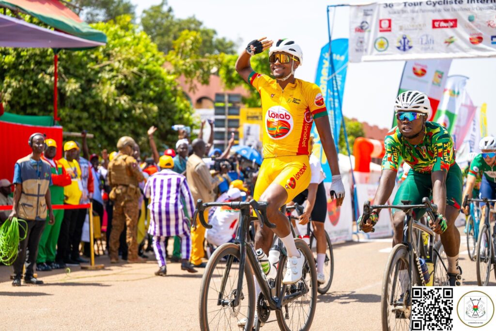 Ibrahim Traoré remet une récompense à un cycliste qui salue le public avec le sourire.