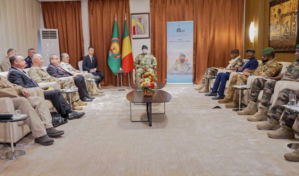 Réunion officielle entre une délégation militaire russe et des responsables militaires au Mali, assis en face à face dans une salle de conférence.