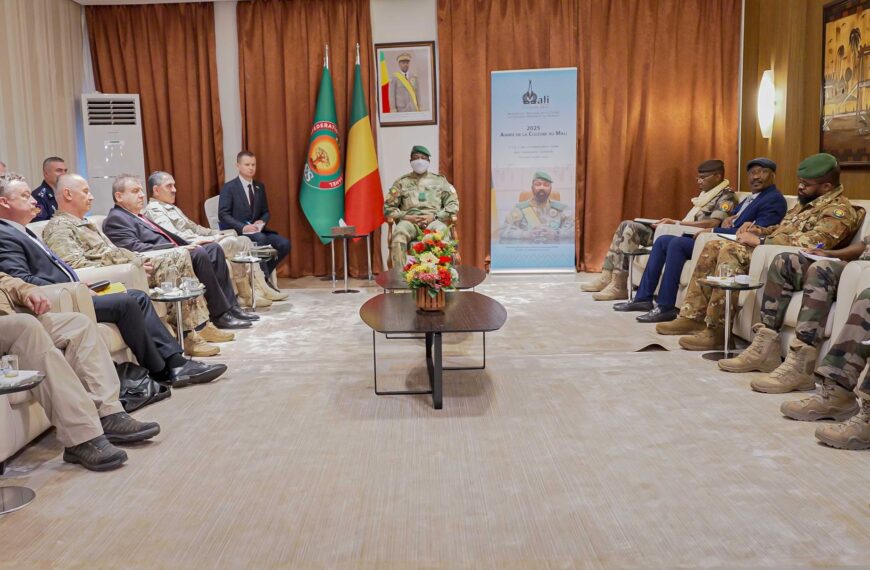 Réunion officielle entre une délégation militaire russe et des responsables militaires au Mali, assis en face à face dans une salle de conférence.