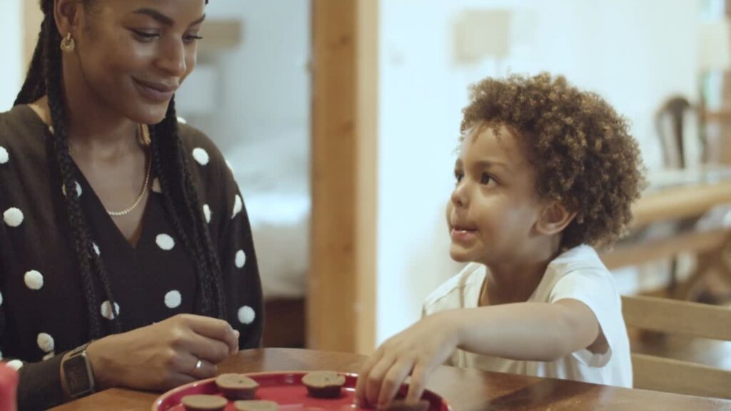 Une mère et son enfant partagent un moment autour de chocolat posé sur une table, dans un cadre familial.