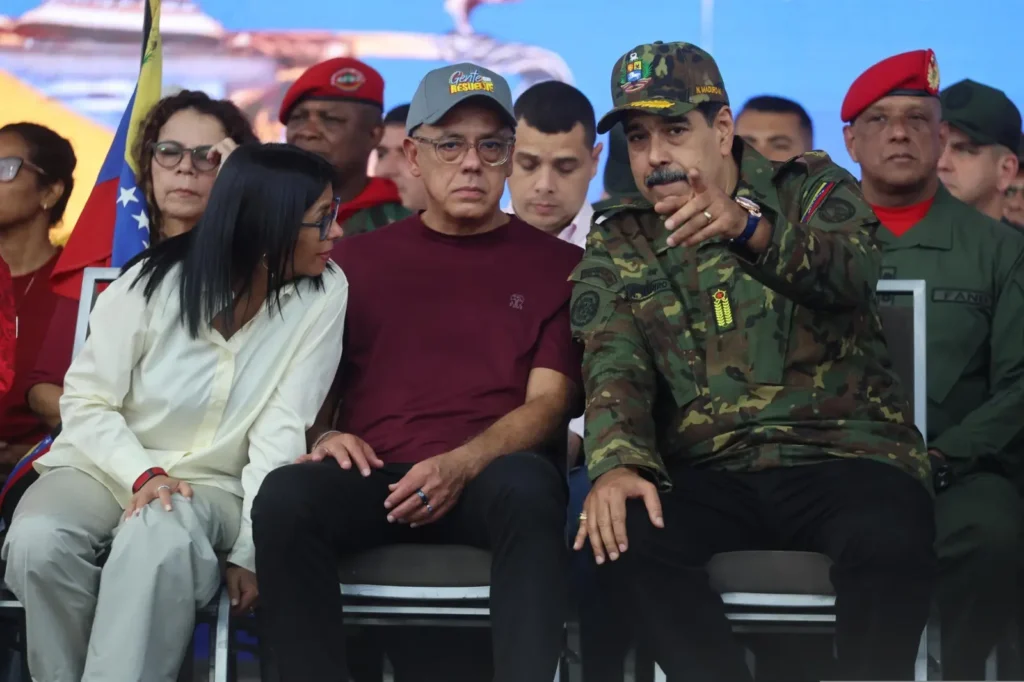 Venezuela : le président Nicolás Maduro assis aux côtés de la vice-présidente Delcy Rodríguez lors d’un événement public, entouré de responsables civils et militaires.