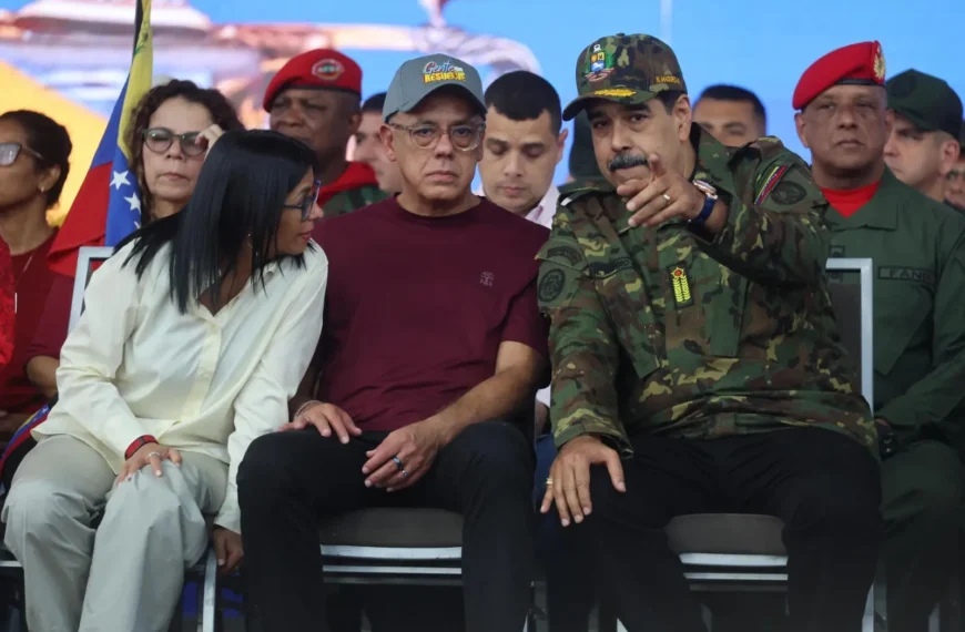 Venezuela : le président Nicolás Maduro assis aux côtés de la vice-présidente Delcy Rodríguez lors d’un événement public, entouré de responsables civils et militaires.